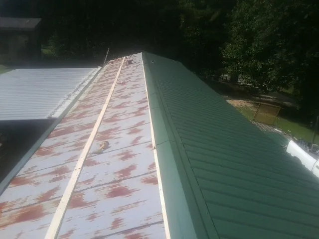 Old rusted panels beside newly installed green metal roofing — Wind Damage Roof Repair by Roofing Brothers in Fishkill