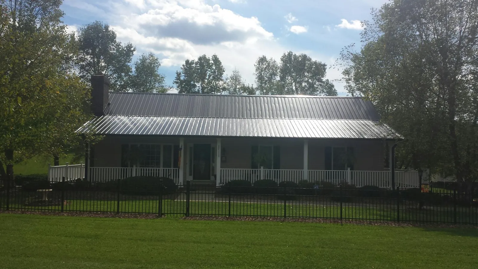 Gray metal roof on a brick ranch with a full width front porch — Gutter Guard Installation work by our crew in Fishkill