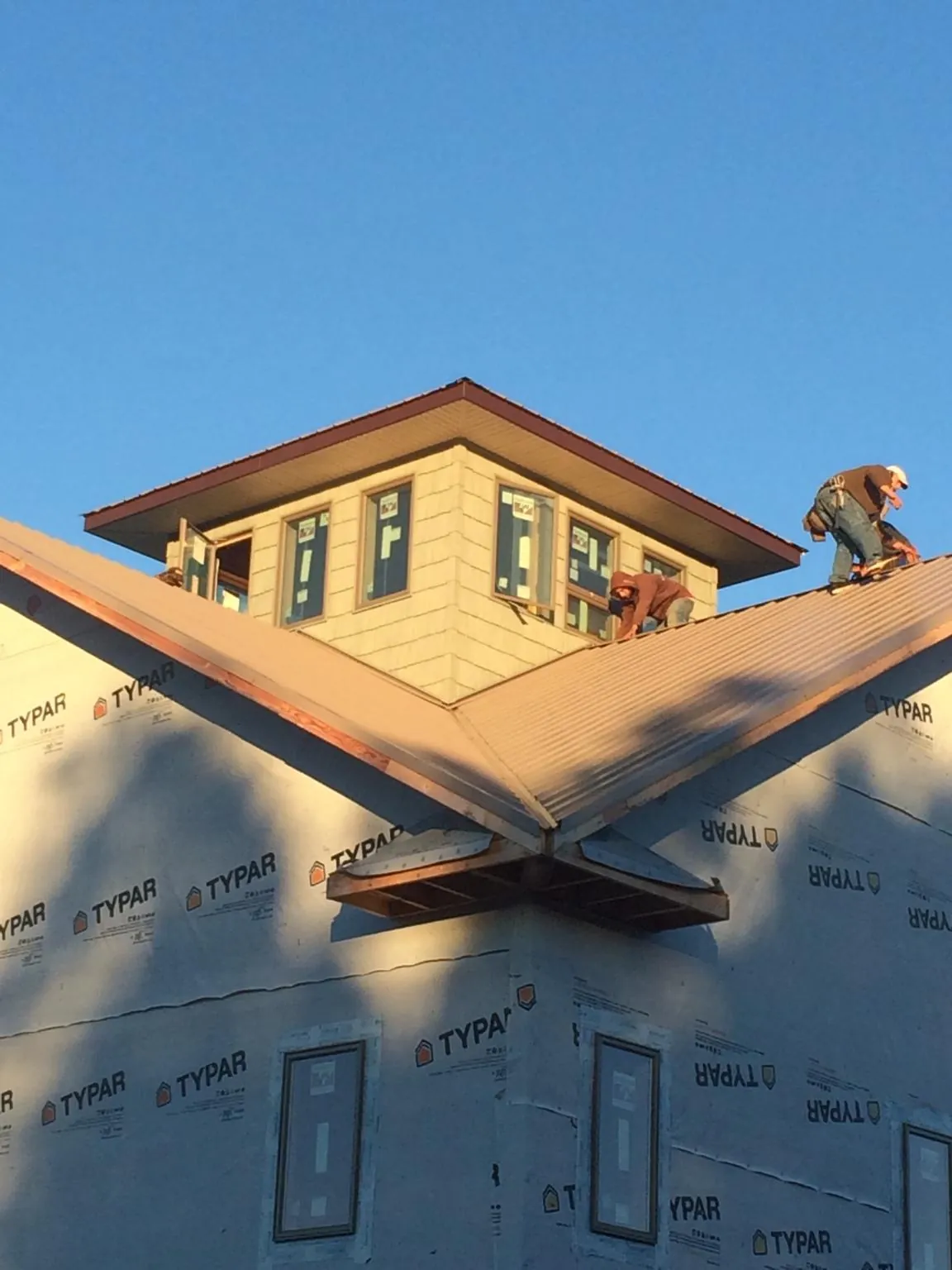 Roofers working around a rooftop cupola on a new metal roof at sunset — Roof Waterproofing in Fishkill by Roofing Brothers